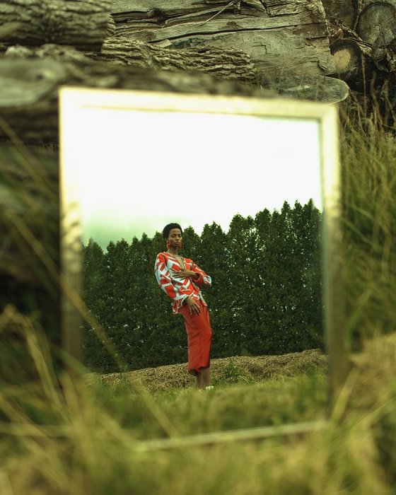 Редакционная фотография зеркала с отражением женщины, стоящей на природе с деревьями на заднем плане