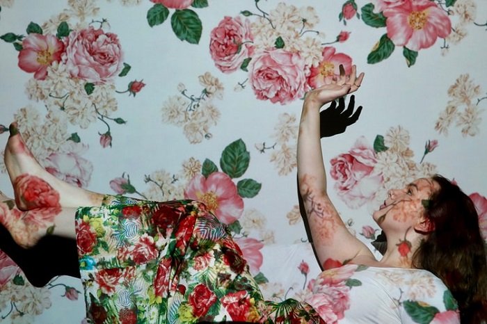 Студийное изображение падающей женщины с цветочной юбкой, фоном и проекцией для редакционной фотографии