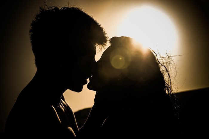 Силуэт целующейся пары, освещенный солнцем как источником света