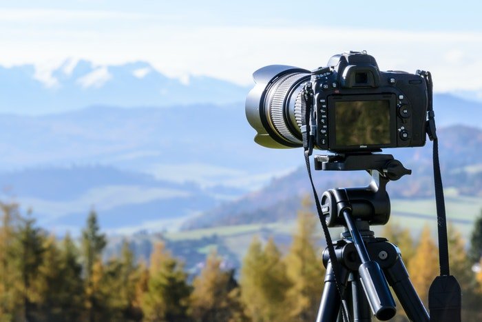 Камера установлена на штативе перед сценой горного пейзажа