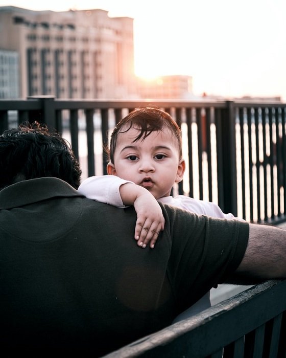 Уличный портрет ребенка, заглядывающего через плечо мужчины