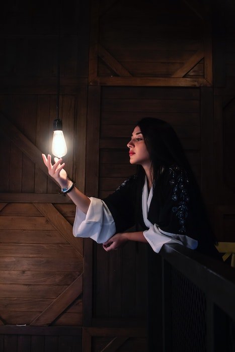 идея фотографии при слабом освещении: одна лампочка освещает портрет женщины