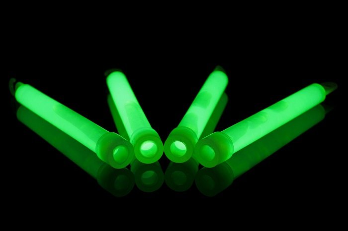 четыре неоново-зеленые светящиеся палочки в абсолютно темной обстановке