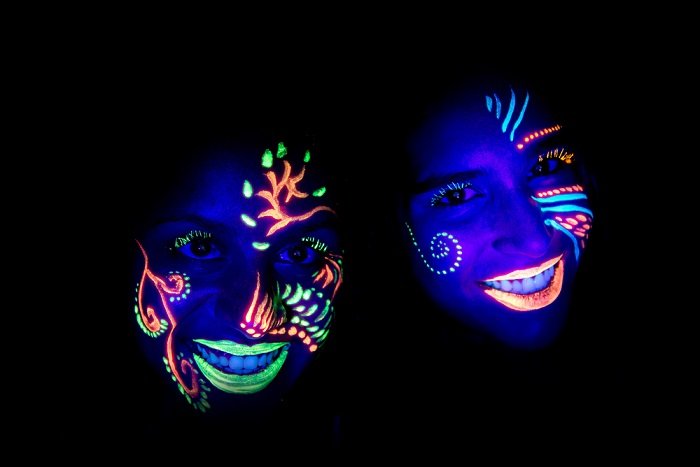 идеи фотографии в черном свете: два человека с ультрафиолетовой краской на лице, снятые в темной комнате