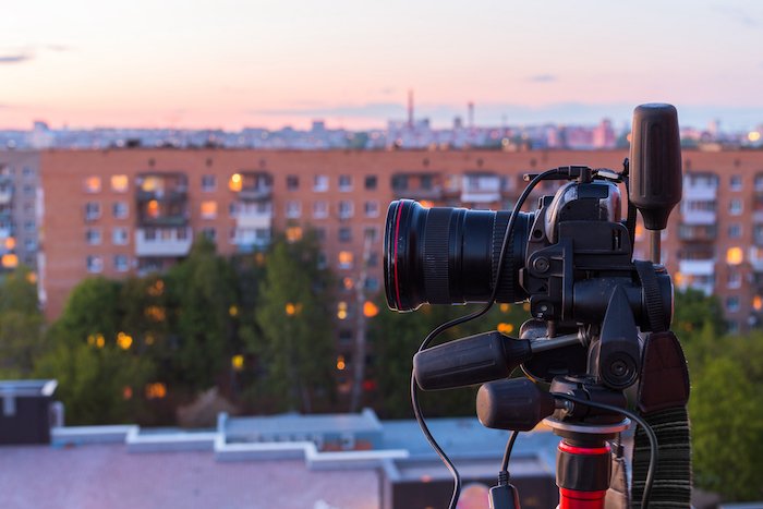 DSLR камера на штативе на фоне вечернего городского пейзажа