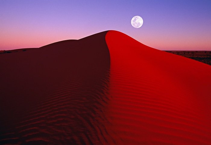 Песчаная дюна с луной на заднем плане в сумерках